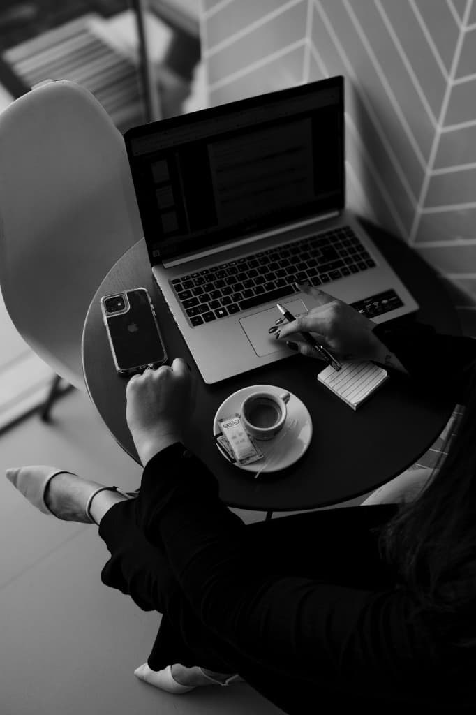 Founder at work: laptop, notebook, and coffee at a quiet table.
