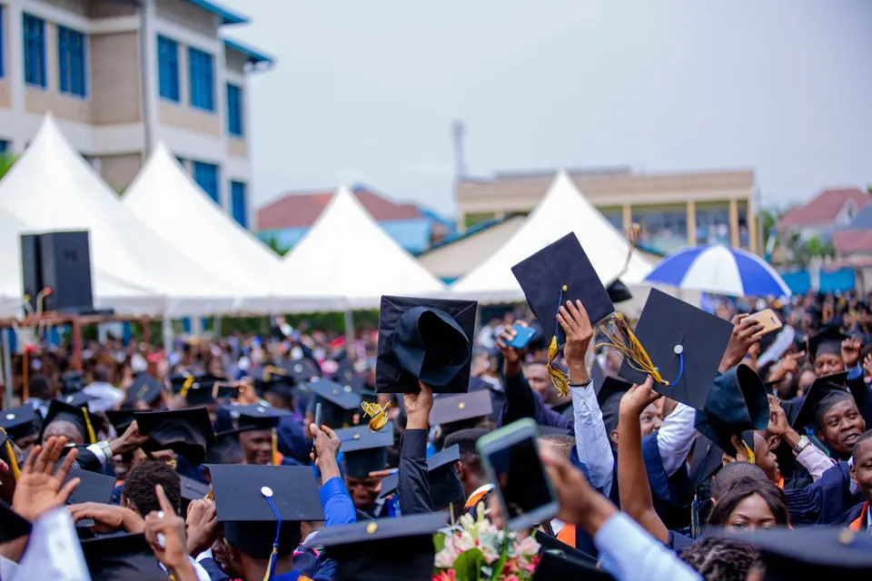 Graduates throwing their caps in the air at an outdoor ceremony