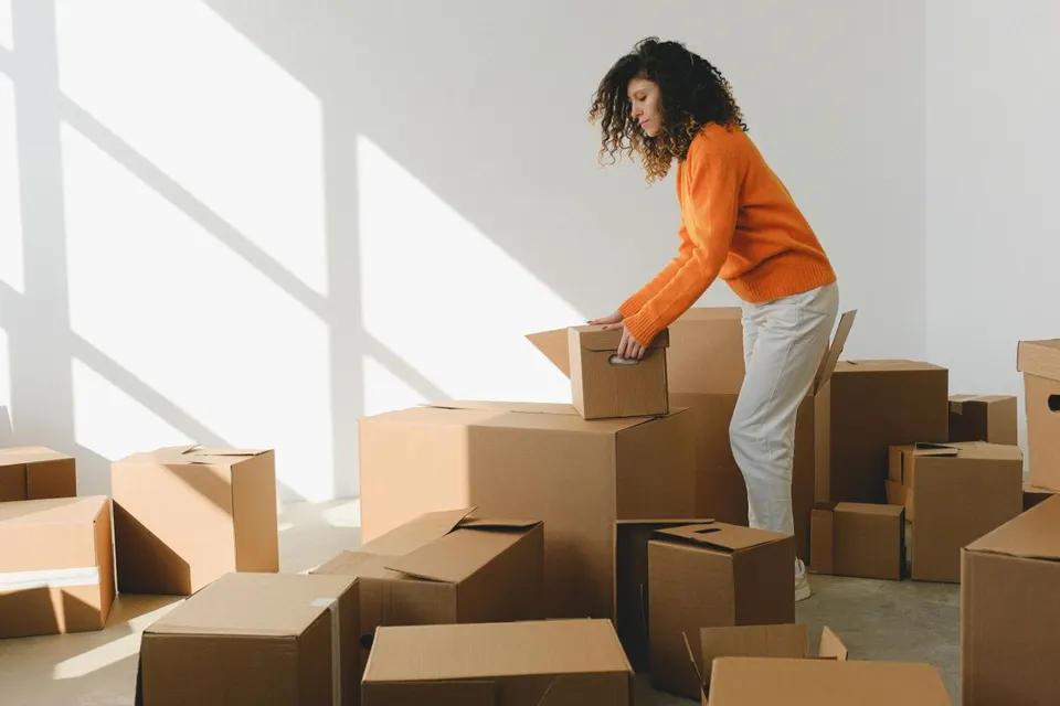 A student unpacking cardboard boxes in a new flat